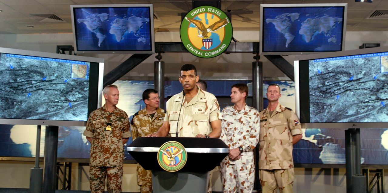 U.S. Brigadier General Vincent Brooks shows off some images on the high tech set at the press center at Camp As Sayliyah outside Doha, Qatar March 22, 2003. Brooks took part in a press conference with U.S. General Tommy Franks and representatives of the coalition forces. Pictured from left are: Rear Adm. Per Tidemand of Denmark, Air Marshall B.K. Burridge of the United Kingdom, Brooks, Brigadier Maurie McNarn of Australia, and Lt. Col. Jan Blom of the Netherlands. General Franks is obscured behing Brooks.