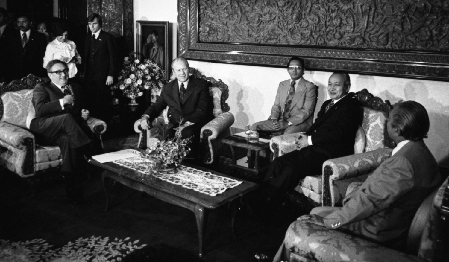 Head to Head Meeting with President Suharto and Foreign Affairs Minister Malik of Republic of Indonesia on President's Far Eastern Trip, sitting on sofas in front of large carved teak wall sculpture telling story of the culture. 1975, December 6 – Jepara Room, Istana Merdeka (Credential Hall) – Jakarta, Indonesia.