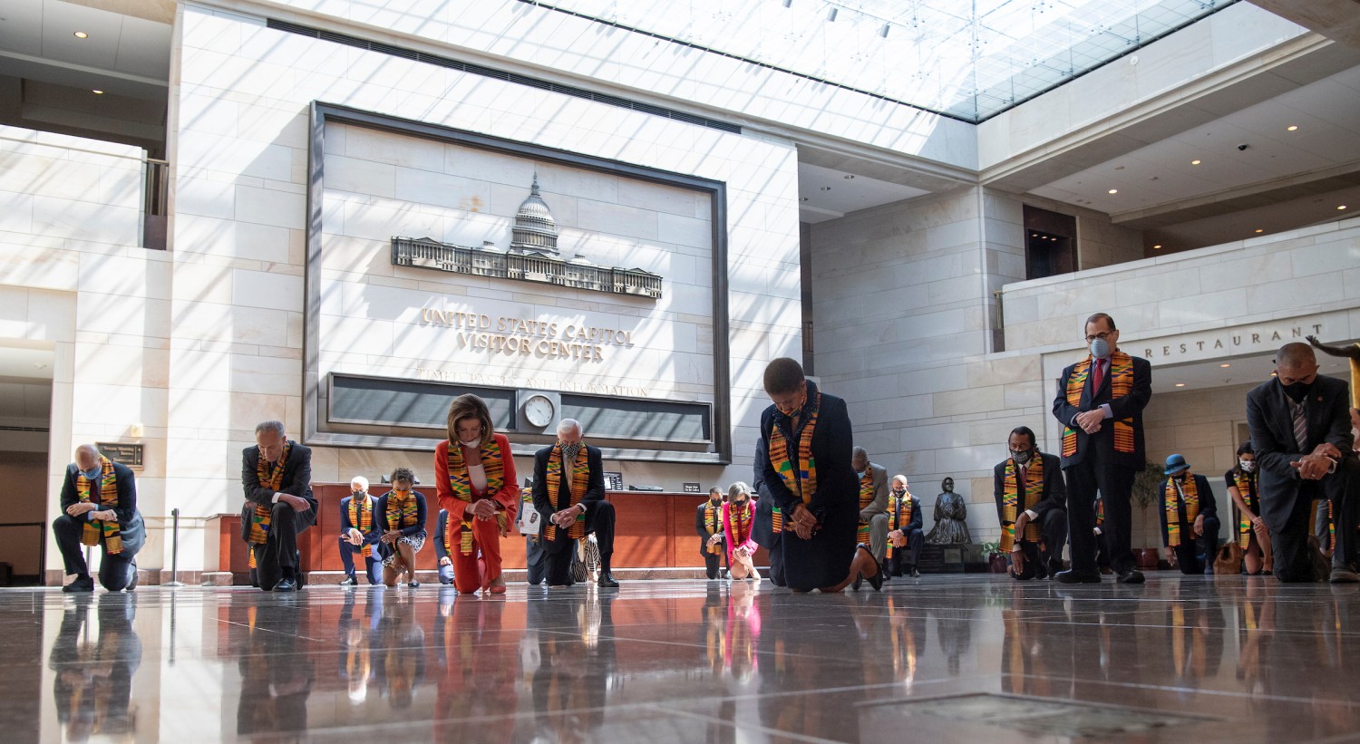 Speaker of the House Nancy Pelosi and other members of Congress kneel inside Emancipation Hall as they observe a moment of silence to honor George Floyd and other victims of racial injustice on June 8, 2020. The members of Congress are wearing Kente cloth stoles.